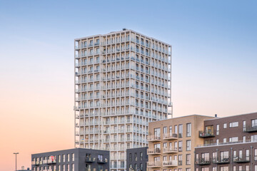 Fototapeta premium Modern Residential Skyscraper and Apartments at Sunset, Grid Facade Architecture, Urban Housing Real Estate Concept