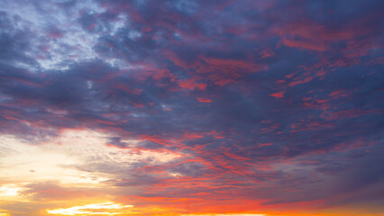 Fototapeta premium Dramatic Sunset Sky with Vibrant Twilight Clouds,Beautiful twilight sky during sunset featuring a dramatic blend of deep blue and purple clouds illuminated with vibrant orange, pink, and yellow hues.