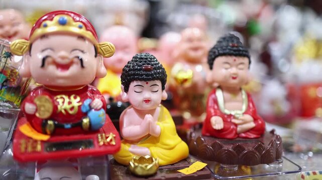 Traditional Vietnamese Tet holiday decoration close up. Cute small statues of Laughing Buddha and monks for feng shui luck at a festive street market souvenir shop in Nha Trang, Khanh Hoa, Vietnam.