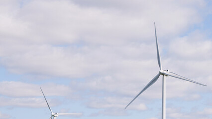 Fototapeta premium Large White Wind Turbines Against a Partly Cloudy Blue Sky