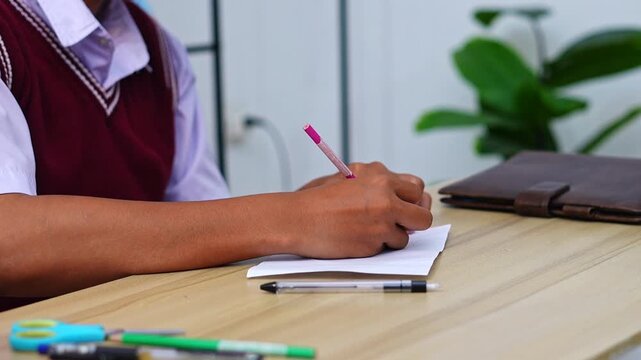 Close-up of hands writing notes on sheet of paper in study setting