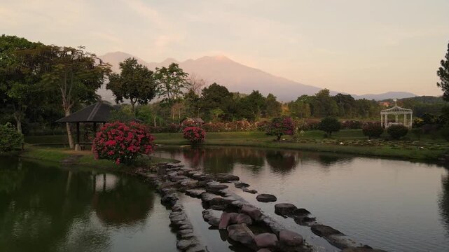 Cinematic drone flight over serene manmade reservoir lake in Malang East Java Indonesia with majestic Gunung Arjuna volcanic peak rising dramatically in background