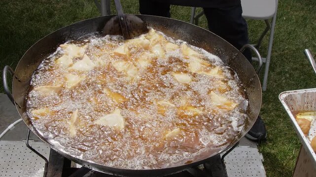 Vegetable samosas deep fry in cauldron oil outside at Indian festival