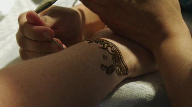 Henna stain is applied to woman's arm in traditional Asian design