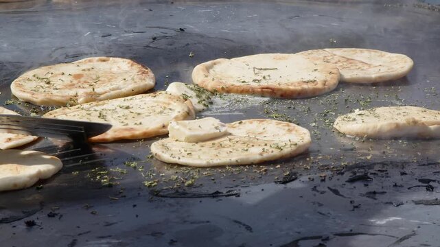 Naan break is cooked on enormous outdoor grill with herbs and ghee