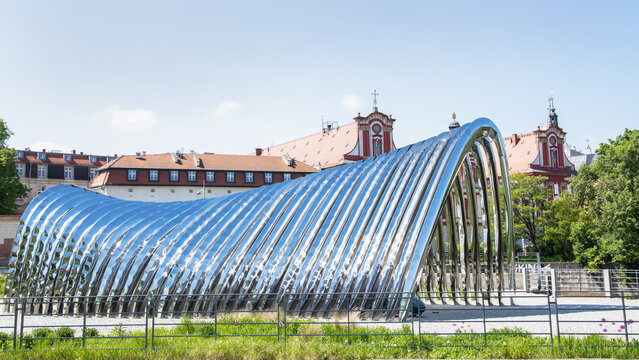 Poland, Wroclaw, 10.05.2026. Futuristic mirror steel arch installation by Oskar Zieta on Daliowa Island with historic city architecture on Odra river