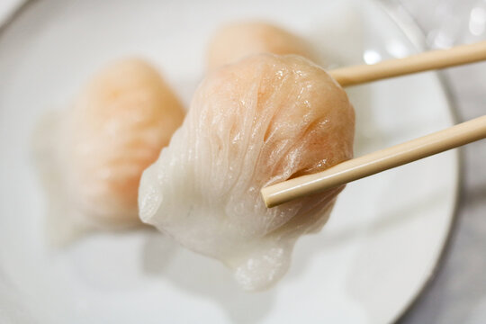 Eating har gow dumplings with chopsticks.