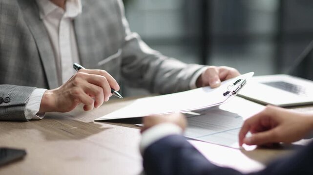 Businesspeople negotiate contract over polished table surface
