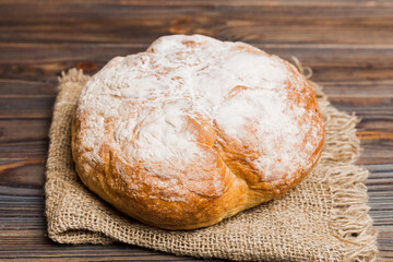 Naklejka premium freshly baked bread with napkin on rustic table top view. Healthy white bread loaf isolated