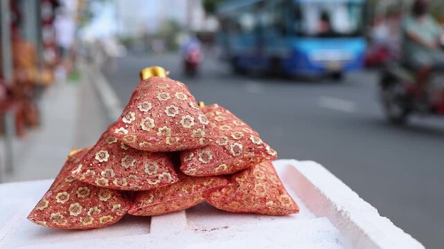 Traditional Vietnamese Tet lucky salt bags for sale on a street. Close-up of festive red and golden brocade pouches on a market display box before Lunar New Year celebration.