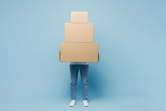 Full body delivery employee young woman wear white uniform workwear work as dealer courier hold in hand big stack cardboard box isolated on plain pastel light blue background studio. Service concept.
