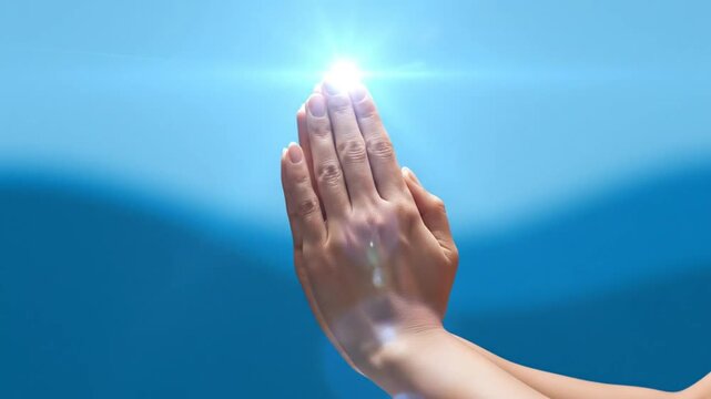 Praying hands with a bright glowing light, faith, spirituality, and hope in a serene blue sky background