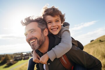 Naklejka premium Happy father giving piggyback ride to his cheerful son with sun flare