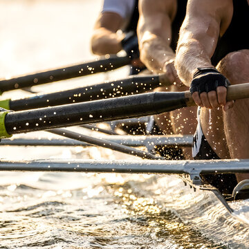 Close up on rowers hands gripping oars during intense water sport race.