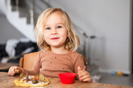 Cute toddler girl smiling while playing with dough