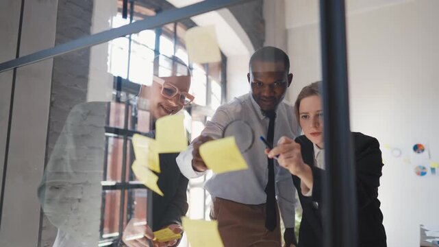 Teamwork in office of international corporation, people reading notes on wall. Coworkers in financial analysis departments, creative team of marketing specialists, developing new strategy for company