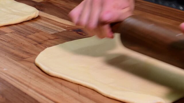 Rolling dough with wooden pin on wooden table in baking scene