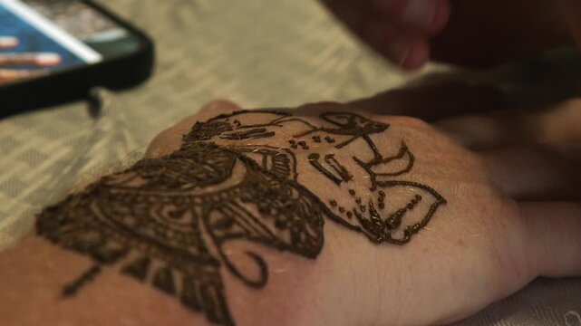 Ganesha tusks drawn onto man's hand in brown henna dye, temporary art