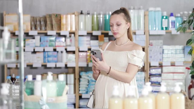 Uncertain young pregnant female client trying to choose medical preparation in chemist's shop