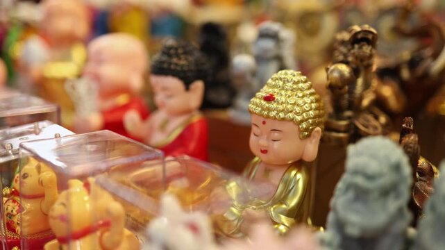Traditional souvenir figurines for sale at a Vietnamese street shop in Nha Trang, Vietnam. Close-up of small golden Buddha statues and lucky cats displayed for tourists at a local outdoor market