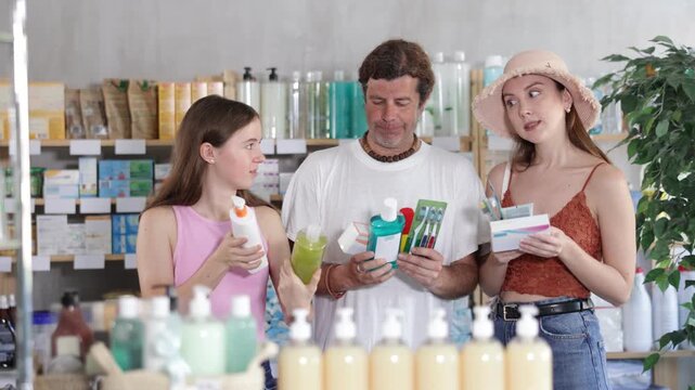 Man with wife and teen daughter customers in drugstore choose with different products. Parapharmacetical products, French body care cosmetic, pills and medicines are in drug store assortment