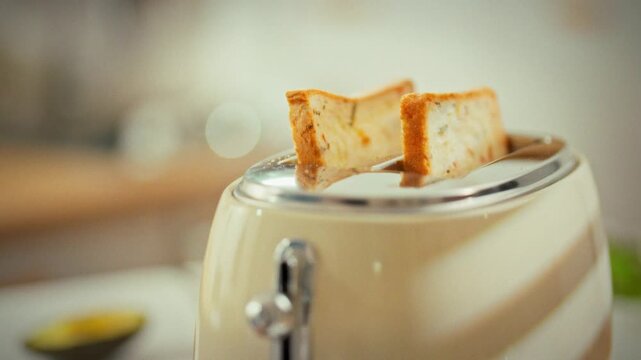 In home kitchen, a toaster ejects a slice of hot toast, signaling the cooking process is complete. The simple act showcases everyday cooking, where a toaster efficiently makes perfectly toasted bread