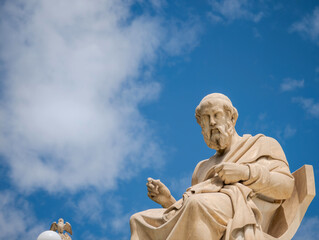 Obraz premium Seated Plato statue framed by open sky and soft clouds, leaving ample copy space for headlines, branding, and modern graphic use.