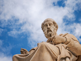 Obraz premium Seated Plato statue framed by open sky and soft clouds, leaving ample copy space for headlines, branding, and modern graphic use.