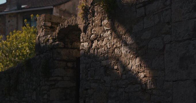 Weathered stone wall with sunlight and shadow details in an old town.