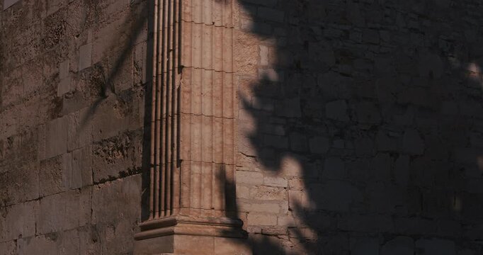Close-up view of a Corinthian column and stone wall at the Temple of Augustus.