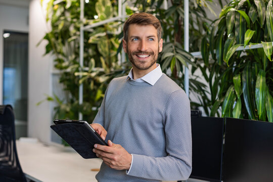 Modern business man in formalwear using digital tablet while standing in the office