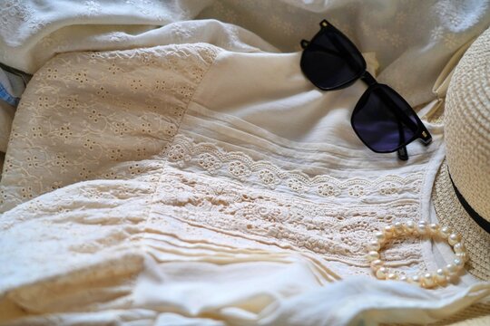 Sunglasses and pearl bracelet on lace dress, elegant fashion flat lay