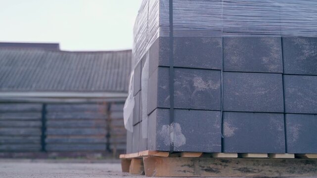 Pallet of grey concrete blocks wrapped in plastic film at construction site