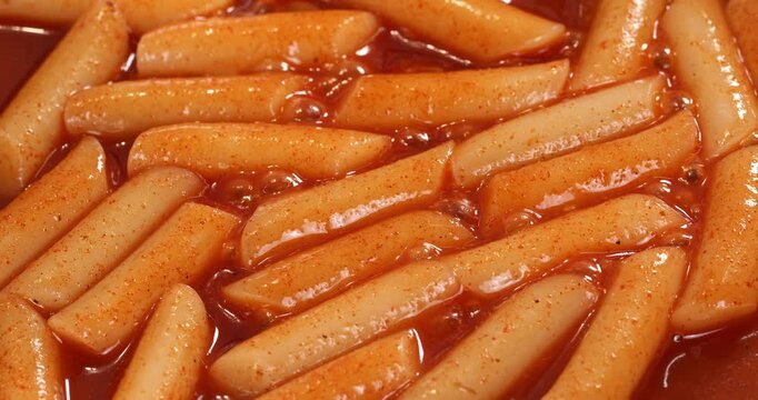 Process of cooking the Korean national dish tteokbokki. The tteokbokki in sauce are fried in a pan.