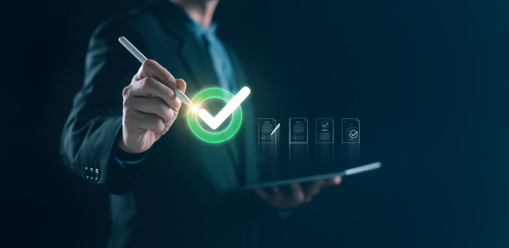 Businessman using stylus on tablet to confirm digital checklist with glowing checkmark, representing approval workflow, data validation,and secure compliance process in a modern corporate environment.