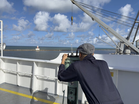 Navigation marine officer get visual bearing to lighthouse by pelorus from the ship navigation bridge wing for correction gyro compass error. 