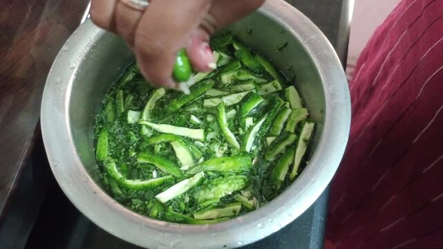Squeezing fresh lemon juice over chopped bitter gourd slices soaked in water, reducing bitterness of karela