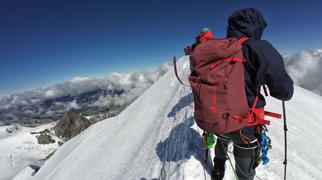 POV mountaineering in rope team with mountaineers on the ridge of Breithorn and mountain glacier panorama in summer in Swiss Alps, canton of Valais, Switzerland