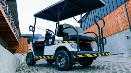 Modern white golf cart with black accents parked on a paved pathway © shine.graphics