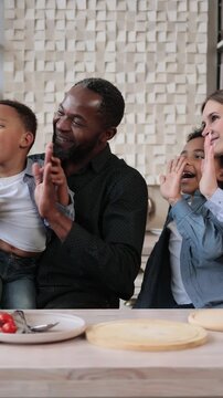A diverse family is happily recording a video blog together in their modern kitchen, surrounded by fresh ingredients