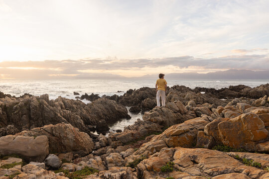 young boy exploring  rocky coastline of DeKelders, Gansbaai, South Africa