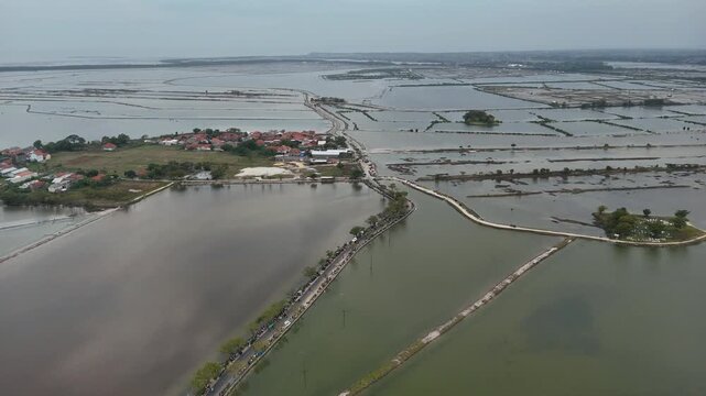 Top down aerial view of coastal fish ponds and road in Indonesia