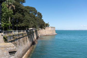 Historic sea wall and boardwalk along the Atlantic Ocean in Cádiz, Spain, offering an ocean view © Carlos