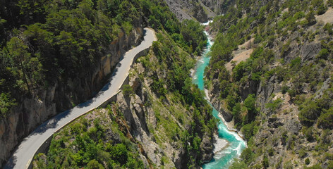 Fototapeta premium DRONE: Flying above an empty asphalt road leading into a tunnel above the river