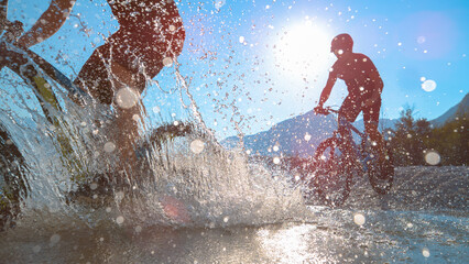 Obraz premium SILHOUETTE: Friends spraying water at camera while riding bicycles in Soca river