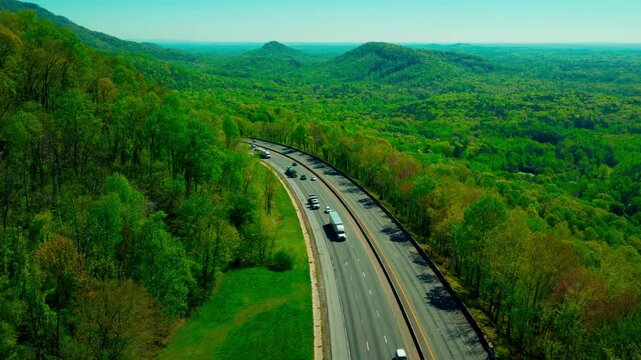 High-angle view of commercial semi-trucks navigating the winding Andrew Jackson Highway near Troy, North Carolina. The backbone of the Southeast shipping corridor.