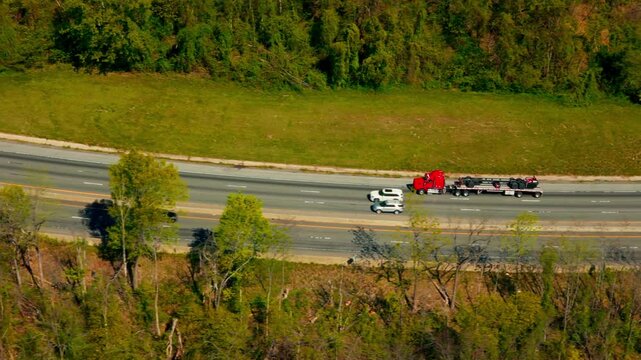 Red commercial flatbed semi truck transporting an industrial load through the mountains. Interstate I-26 North Carolina, USA
