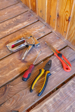 Manual tools including pliers, cutter and stapler gun on wood.