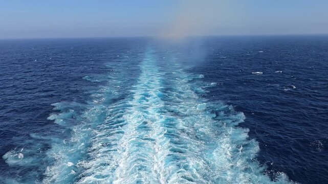 Cruise ship wake stretching across blue ocean water