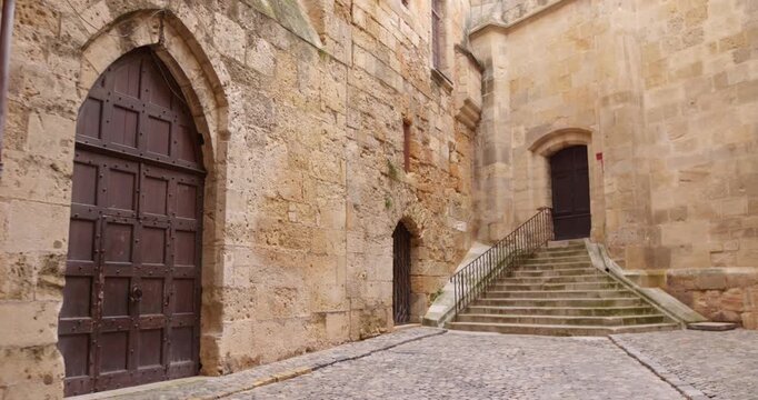Medieval stone walls, Gothic arched wooden door, and stone staircase at the Archbishop's Palace in Narbonne, southern France.